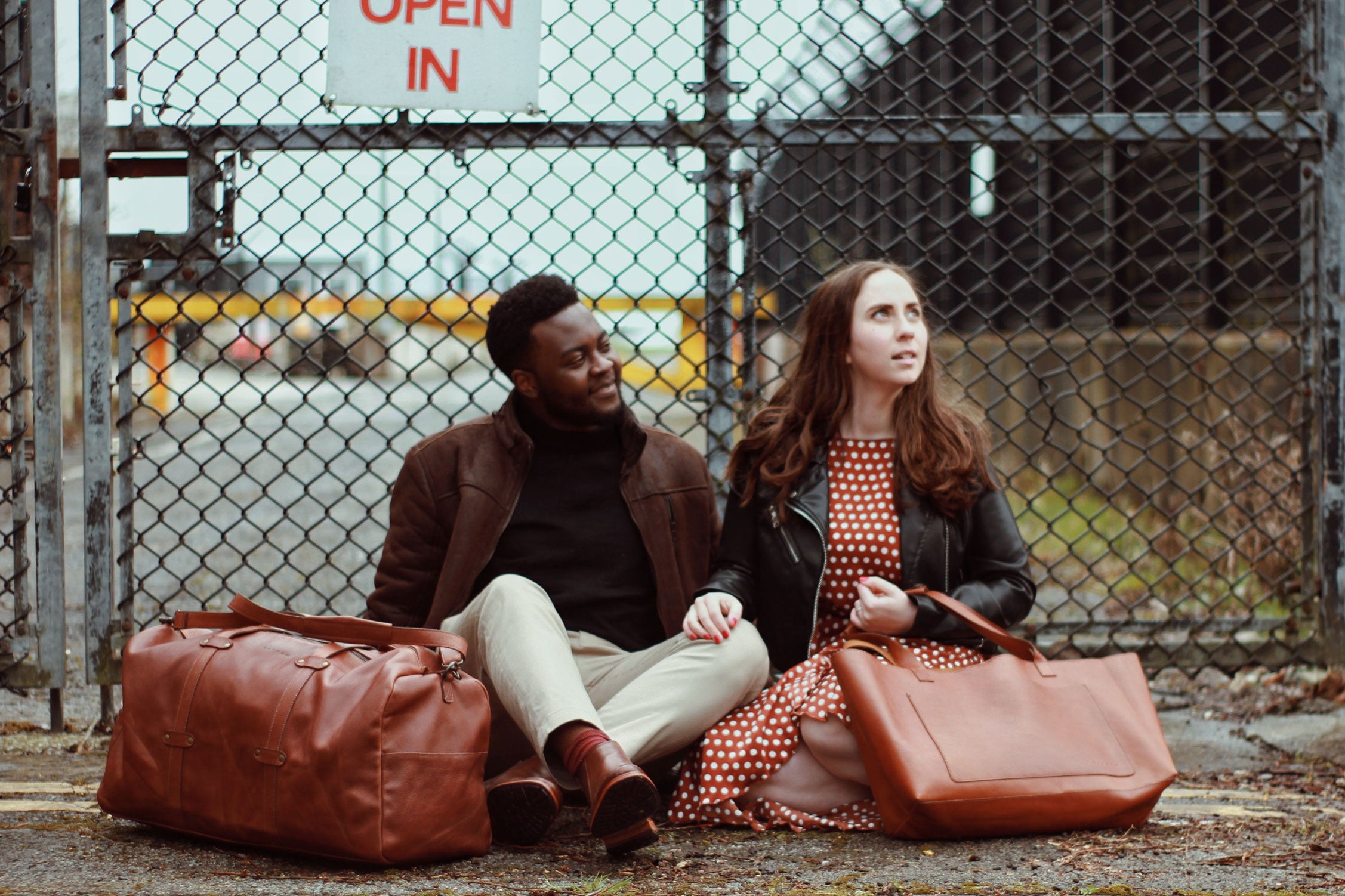 A man and a woman sitting next to the Leather Travel Duffle & Leather Tote by Bayraw